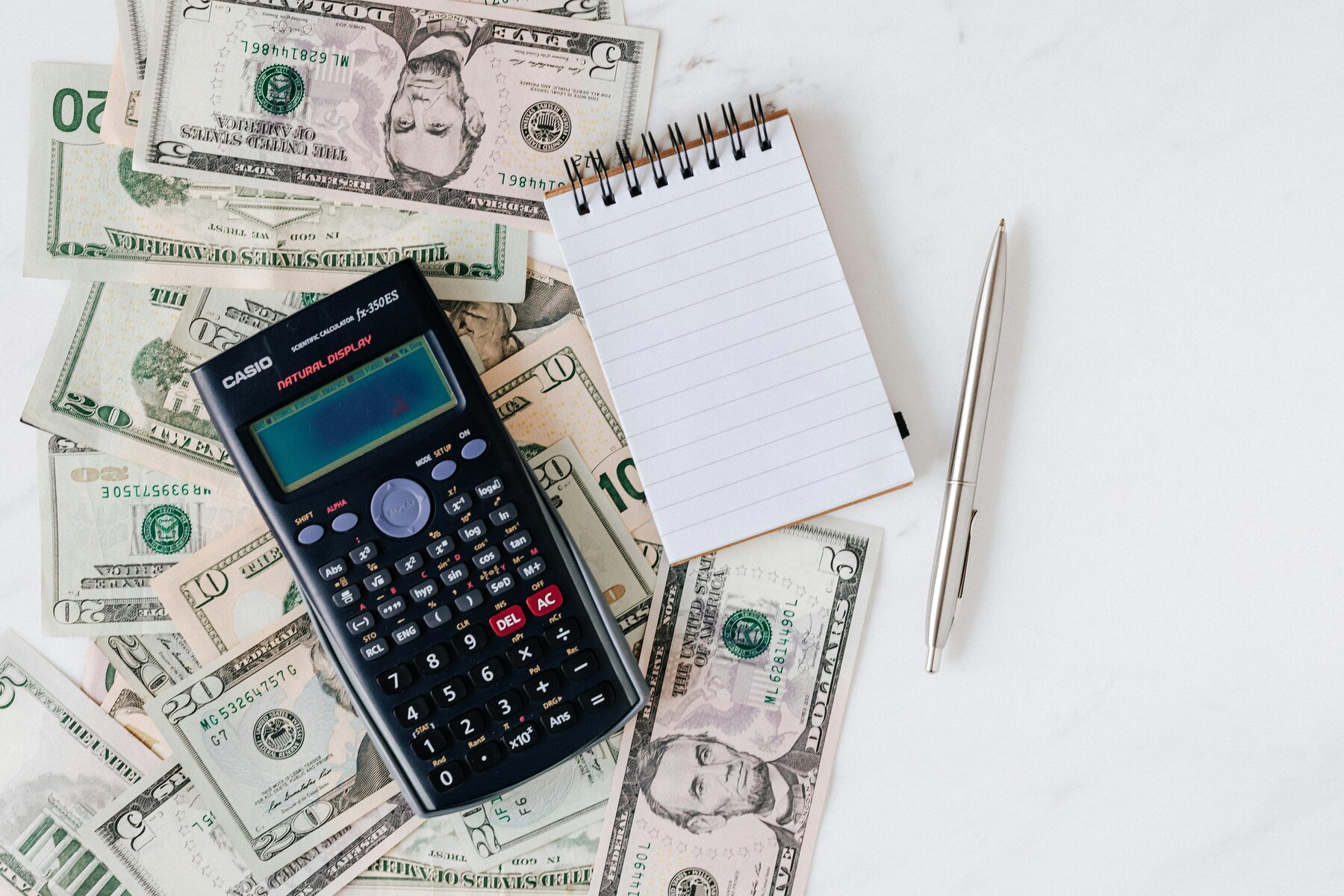Flat lay of US dollar bills with calculator and notebook for budgeting. Montenegro real-estate taxes — a concise guide for our real estate clients