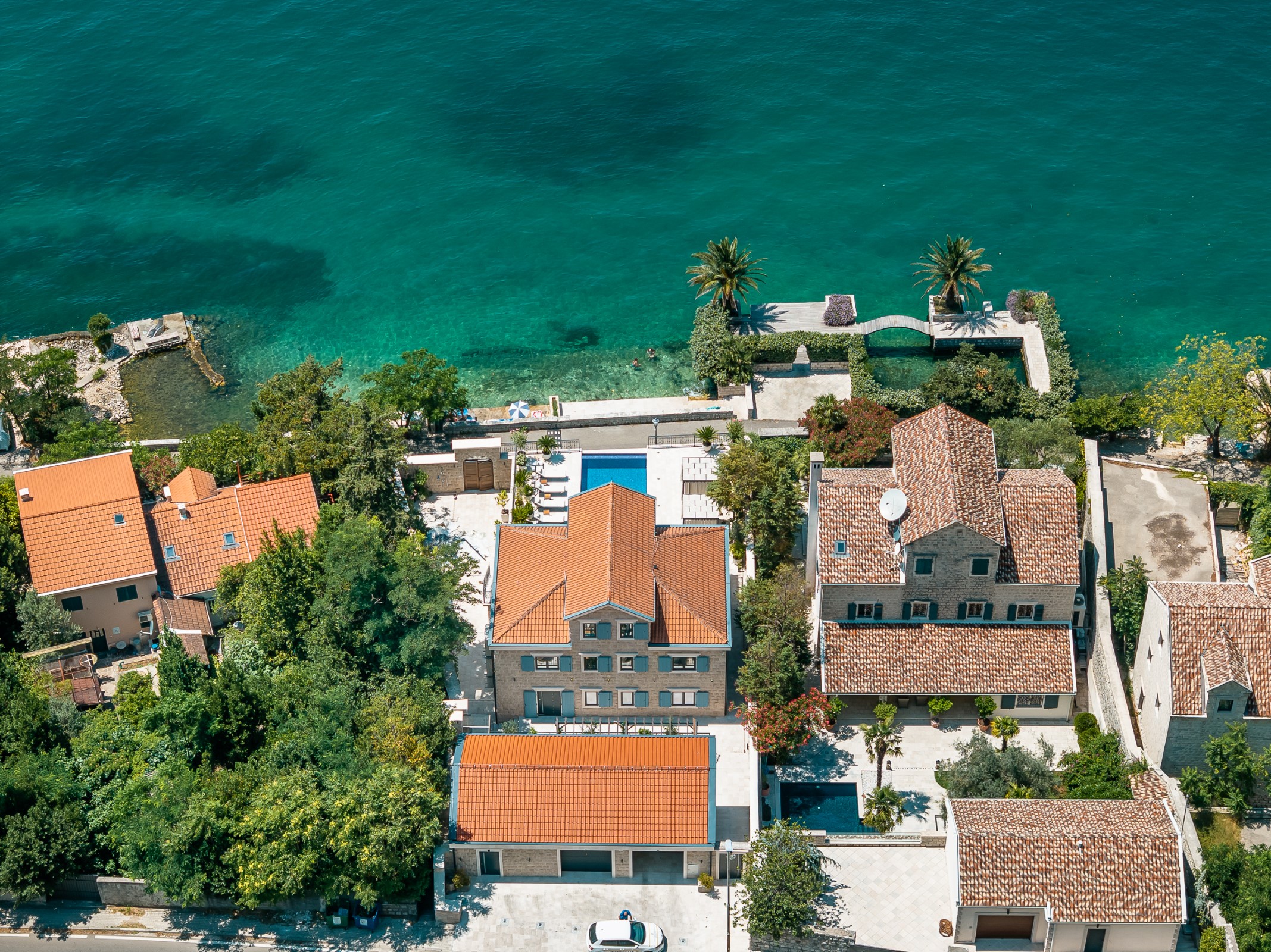 Breathtaking aerial view of luxurious waterfront homes and villas in Montenegro, showcasing stunning architecture and lush greenery.