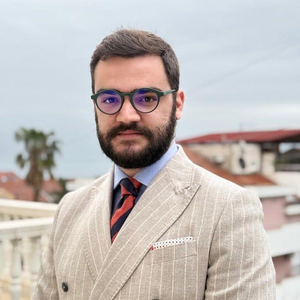 Elegant man in a beige pinstripe suit with glasses outdoors, stylish and professional portrait.