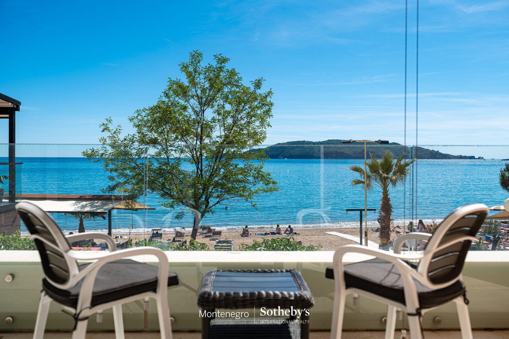 Elegant seaside view from a luxury Montenegro apartment overlooking the Adriatic Sea with outdoor seating and lush greenery.