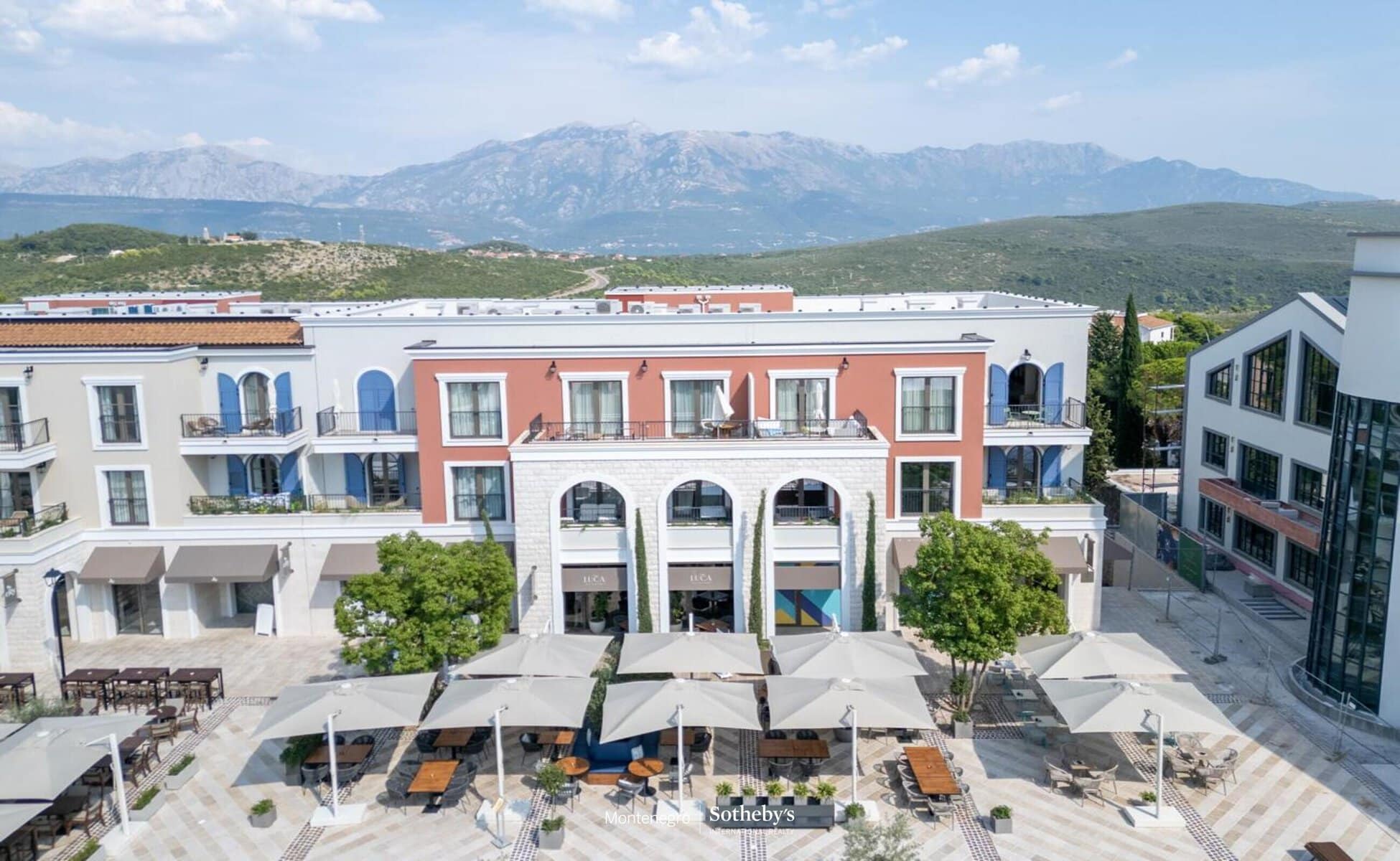 Luxury real estate Montenegro: Modern apartment with outdoor seating and mountain view.