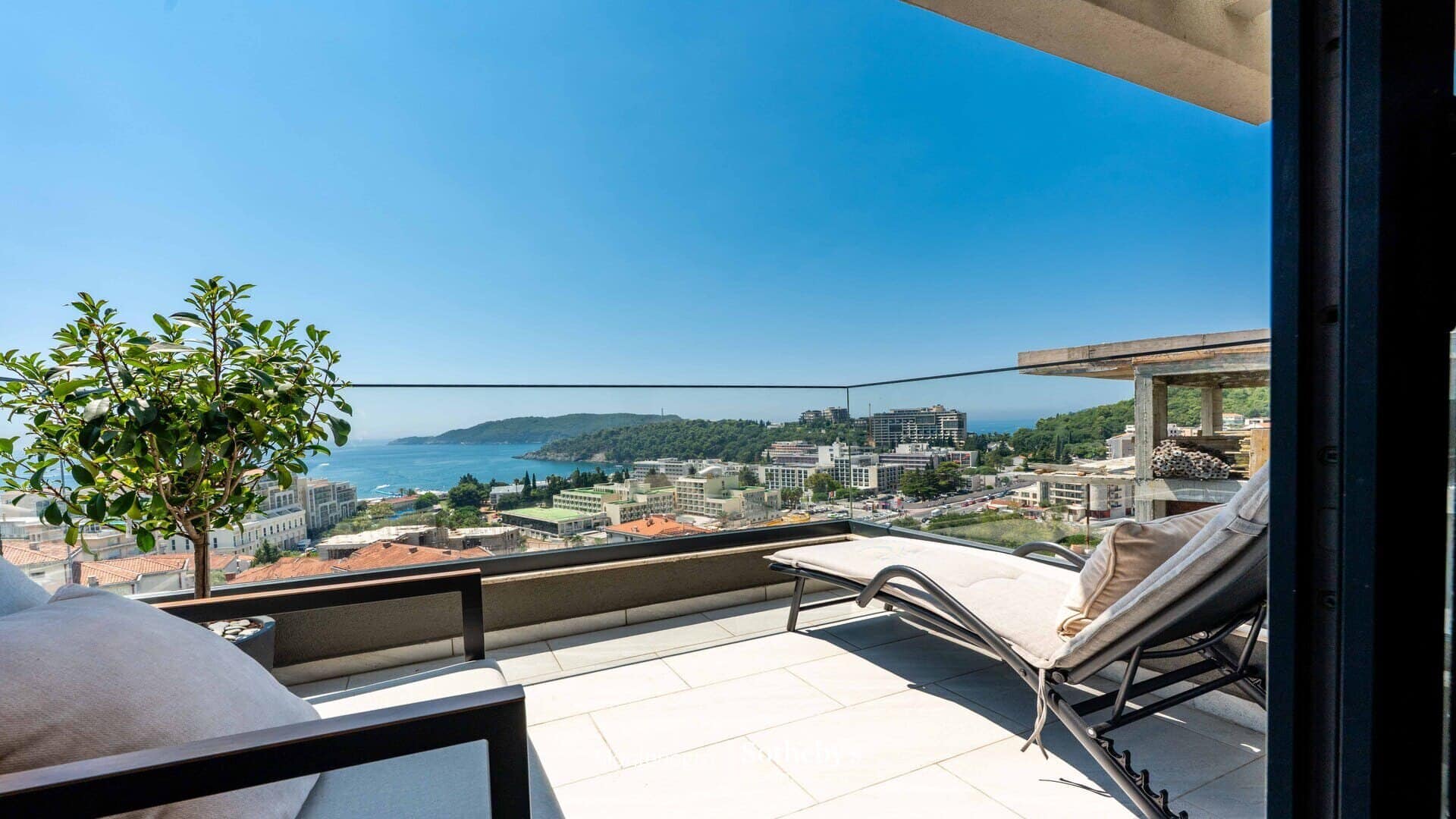 Luxury real estate Montenegro: Balcony view with sea and cityscape.